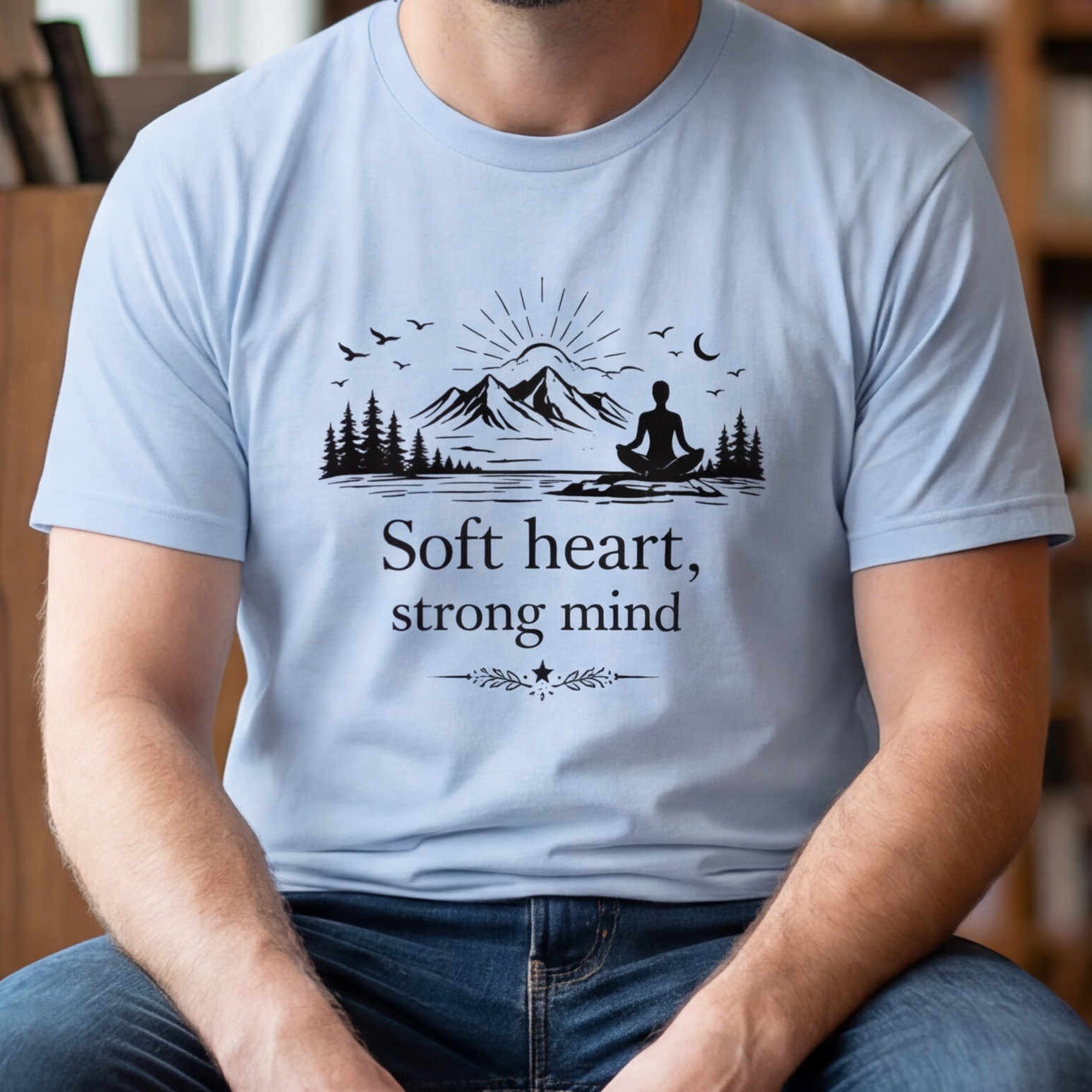 Man sitting on a stool in a bookstore wearing a t-shirt with text and graphics.